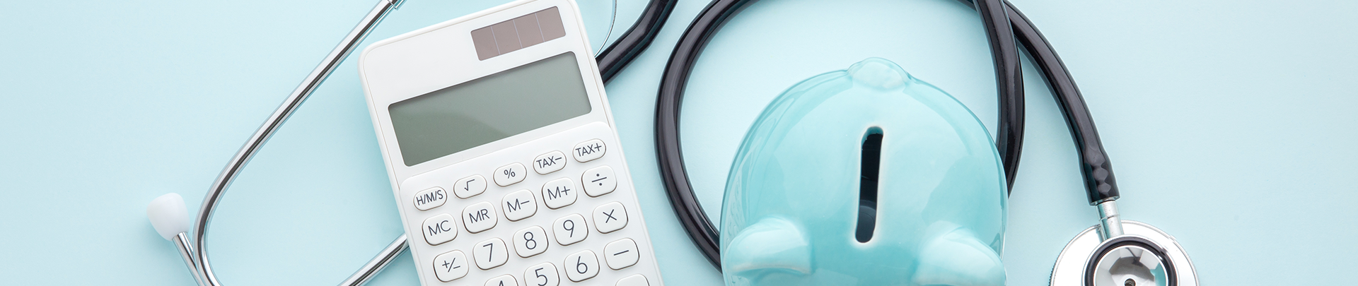 Zorgpremie: stethoscoop, blauw spaarvarken, rekenmachine op een blauwe achtergrond
